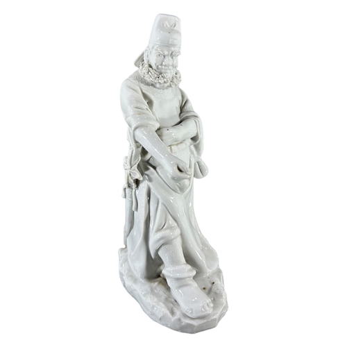 136 - A CHINESE LATE QING DYNASTY BLANC DE CHINE FIGURE OF A MAN WITH HOLSTERED SWORD, PROBABLY CAO GUOJIU... 