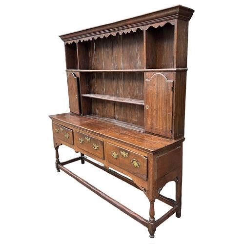 250 - AN 18TH CENTURY OAK DRESSERThe cornice above a shaped apron and shelves and two cupboard doors above... 