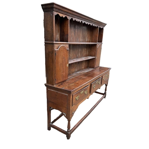 250 - AN 18TH CENTURY OAK DRESSERThe cornice above a shaped apron and shelves and two cupboard doors above... 