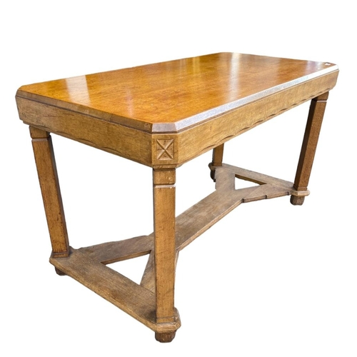 204 - A 20TH CENTURY OAK COTSWOLD SCHOOL DINING TABLEThe counted corner top with carved freeze, raised on ... 