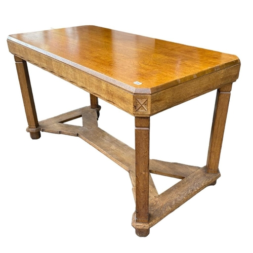 204 - A 20TH CENTURY OAK COTSWOLD SCHOOL DINING TABLEThe counted corner top with carved freeze, raised on ... 