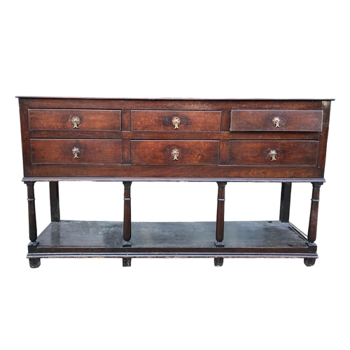 234 - AN 18TH CENTURY OAK DRESSER BASEWith six drawers supported on four gun barrel legs joined by a shelf... 