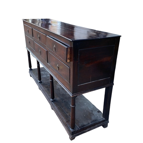 234 - AN 18TH CENTURY OAK DRESSER BASEWith six drawers supported on four gun barrel legs joined by a shelf... 