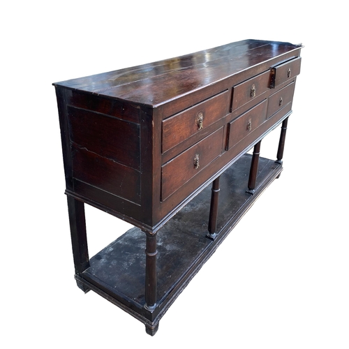 234 - AN 18TH CENTURY OAK DRESSER BASEWith six drawers supported on four gun barrel legs joined by a shelf... 