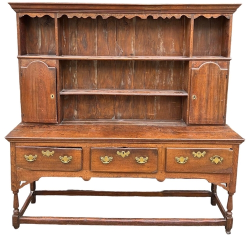 227 - AN 18TH CENTURY OAK DRESSERThe cornice above a shaped apron and shelves and two cupboard doors above... 