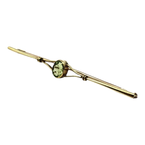 79 - AN EDWARDIAN 15CT GOLD AND GREEN CRYSTAL BAR BROOCHHaving oval cut green crystal, set in open worke... 