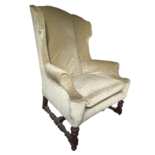 26 - A 17TH CENTURY DESIGN OAK WINGBACK UPHOLSTERED ARMCHAIR
Raised on turned legs joined by a stretcher.... 