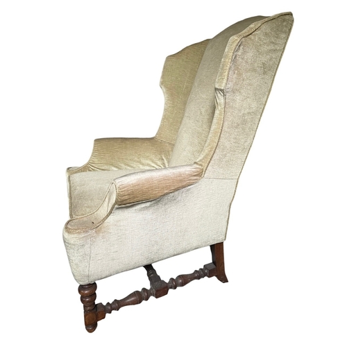 26 - A 17TH CENTURY DESIGN OAK WINGBACK UPHOLSTERED ARMCHAIR
Raised on turned legs joined by a stretcher.... 