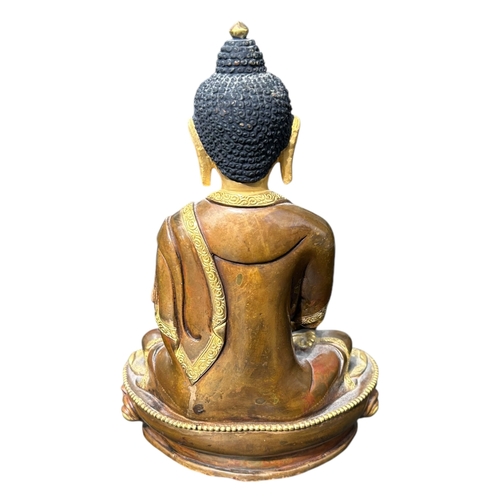 116 - A BRONZE AND GILT FIGURE OF SHAKYAMUNI. 
(h 20cm x w 13.5cm x d 9cm)