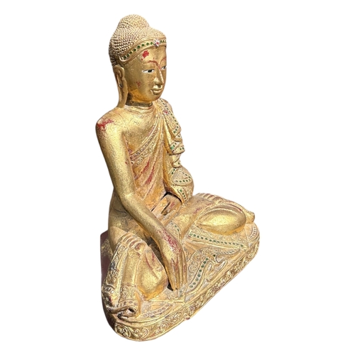 140 - A BURMESE CARVED WOOD AND GILT FIGURE OF A SEATED BUDDHA
Encrusted with various coloured glass decor... 