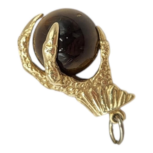 40 - A LARGE 9CT GOLD AND TIGER'S EYE EAGLES CLAW AND BALL CHARM, HALLMARKED LONDON, 1966. 
(h 25mm x w 1... 