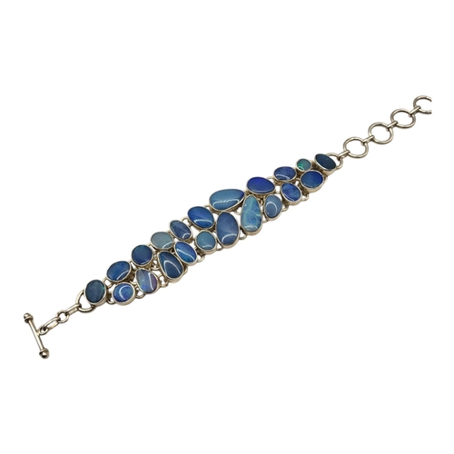 88 - A VINTAGE DESIGNER STYLE SILVER AND FLAT CABOCHON OPAL BRACELET
Having twenty one flat opals (larges... 