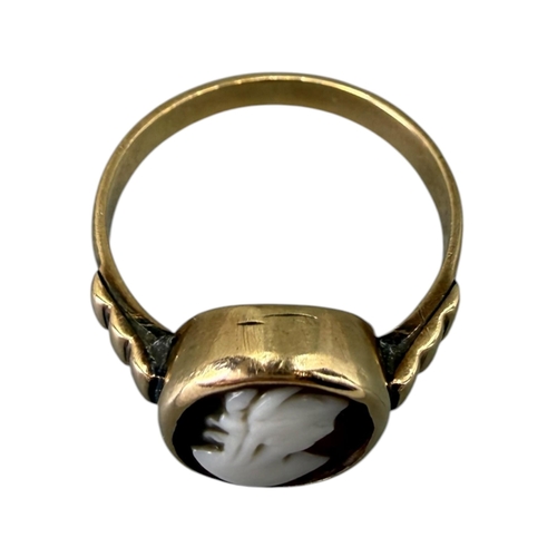 521 - A LATE VICTORIAN 12CT GOLD AND CARVED SHELL CAMEO RING
Oval form, carved shell cameo depicting a bus... 