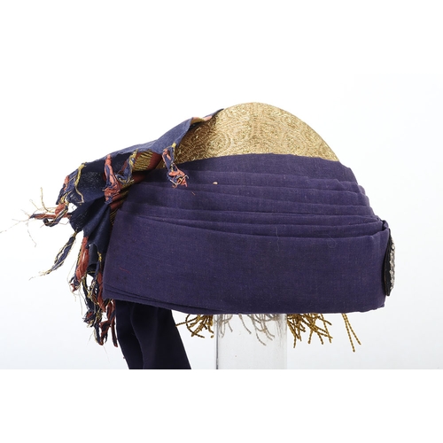 52 - Indian Turban, of recent manufacture, made from blue cloth with gilt embroidery and badge ( glued to... 