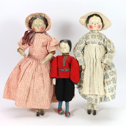 53 - Three carved and painted wooden peg dolls, all with painted blue eyes and black hair, the two larger... 