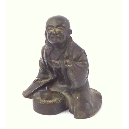 449 - A Japanese bronze figurine depicting a seated workman with a pipe.  60mm tall