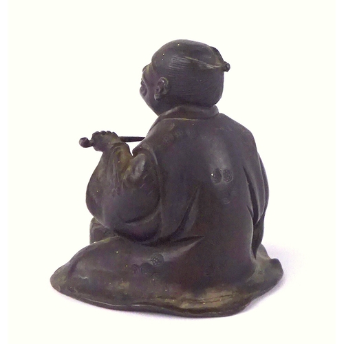 449 - A Japanese bronze figurine depicting a seated workman with a pipe.  60mm tall