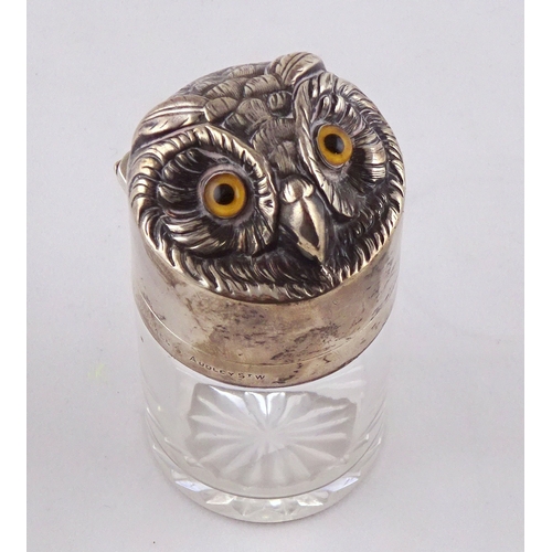 44 - A glass salts bottle having a hinged silver lid styled as an owl's head, inner glass stopper lacking... 
