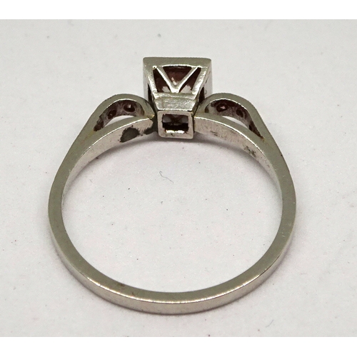 105 - A ring comprising a single brilliant cut white stone set in a square setting with raised, stone set ... 
