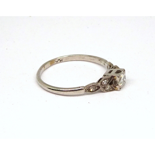 107 - A ring comprising a single brilliant cut white stone set in a square setting with stone set shoulder... 