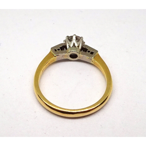 112 - A ring comprising a central brilliant cut white stone in a raised claw setting with baguette cut whi... 