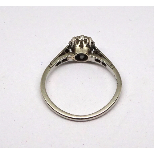 113 - A ring comprising a brilliant cut white stone in a raised claw setting with stone set shoulders, unm... 