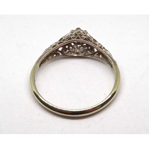 116 - A ring comprising an old cut white stone in a claw setting on openwork shoulders, white metal marked... 