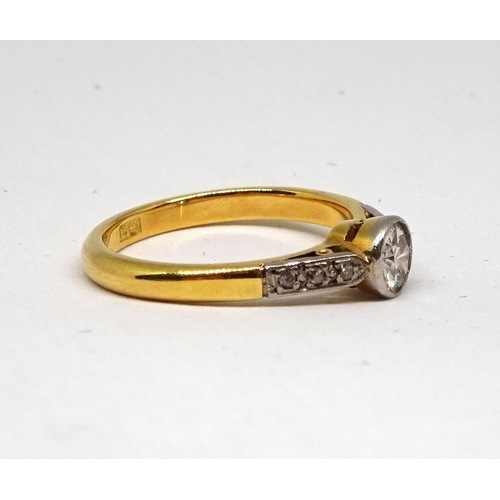 125 - A ring comprising a single brilliant cut white stone in a rub-over circular setting with stone set s... 