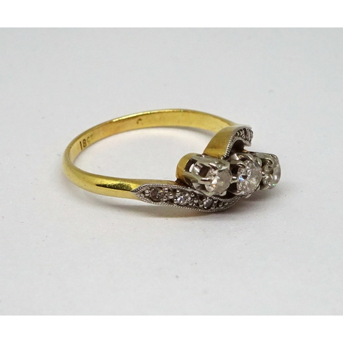 136 - A trilogy ring comprising three white stones in a raised claw setting with six further small white s... 