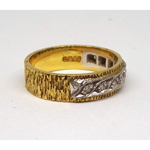 158 - A band ring comprising nine small brilliant cut white stones in a white metal setting on a bark text... 