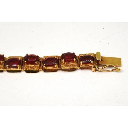 83 - A panel bracelet of textured design, yellow metal set with twenty amber coloured oval stones in an o... 