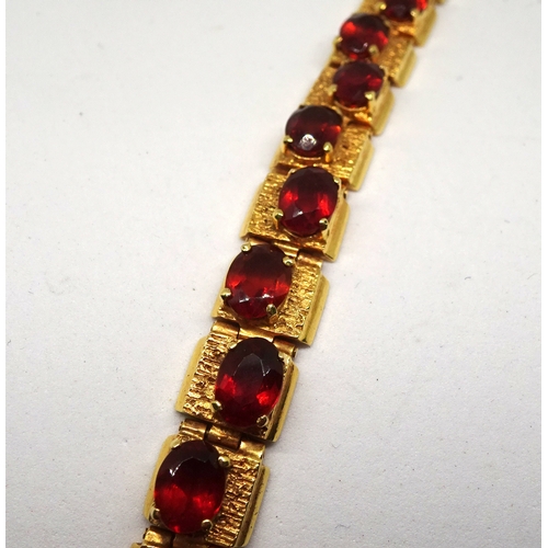 83 - A panel bracelet of textured design, yellow metal set with twenty amber coloured oval stones in an o... 