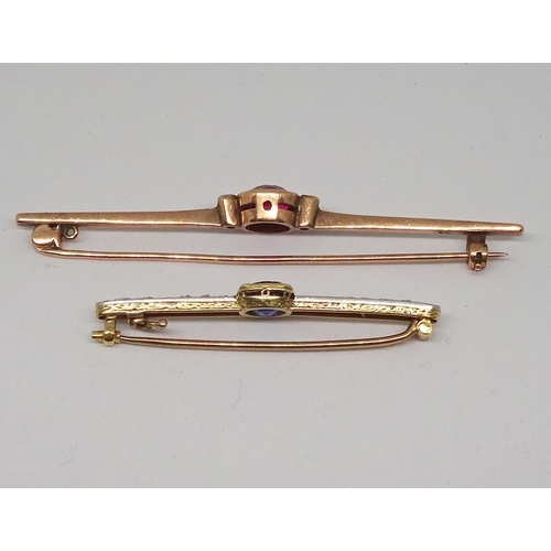 93 - A bar brooch marked 9ct and set with a central brilliant cut red stone, 68mm long / stone 7.5mm diam... 