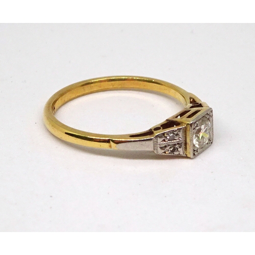 99 - A ring comprising a single brilliant cut white stone set in a square setting with raised, stone set ... 