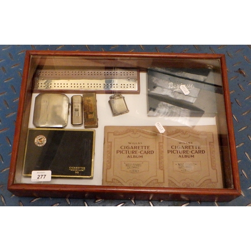 277 - A silver cigarette case, cigarette cards, cigarette lighters etc contained in a glazed display case