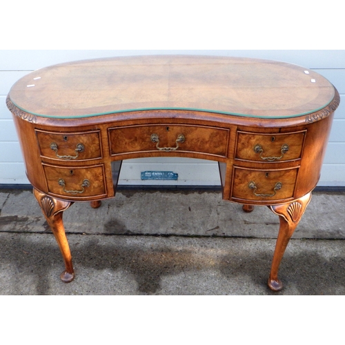 557 - A walnut kidney shaped dressing table, 113cm wide.