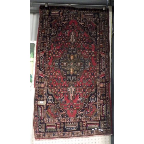 85 - A red ground rug. 108cm x 190cm a/f.