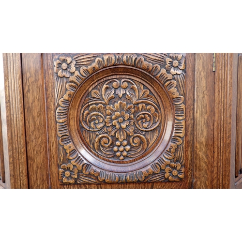 830 - A 1930's carved oak hall wardrobe, cracked central panel, 106cm wide, 45cm deep, 190cm tall