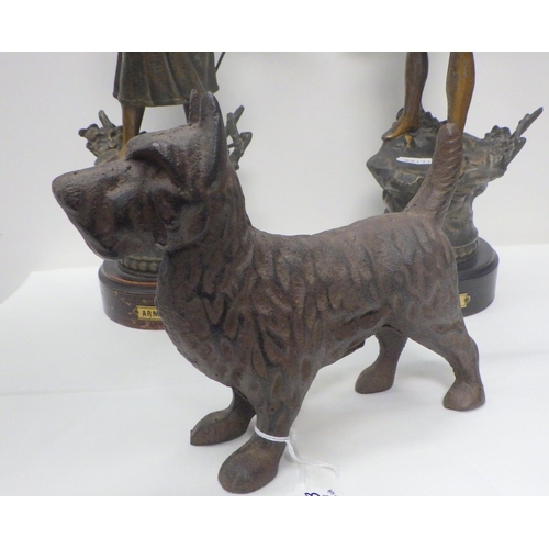 101 - A pair of spelter figurines, 38cm tall; a cast iron terrier figurine.  (3)