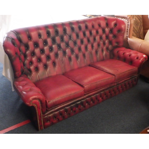 880 - A red buttoned leather three seat sofa, missing two buttons