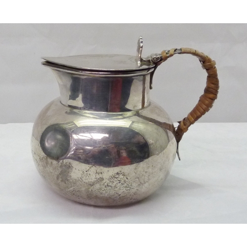 419 - A silver jug having a cane wrapped handle and hinged lid, early 20th cent.  A/F binding damaged, den... 