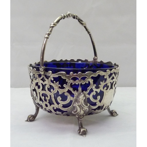 423 - A Victorian silver swing-handled sugar basin having pierced scrollwork design incorporating an engra... 