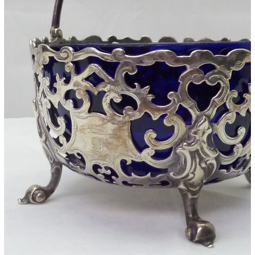 423 - A Victorian silver swing-handled sugar basin having pierced scrollwork design incorporating an engra... 