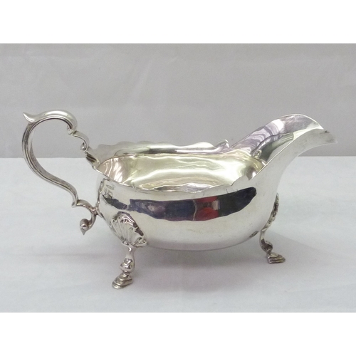 424 - A silver sauce boat standing on scallop mounted hoof feet; a silver toast rack, both early 20th cent... 