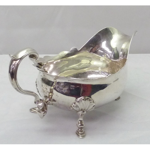 424 - A silver sauce boat standing on scallop mounted hoof feet; a silver toast rack, both early 20th cent... 