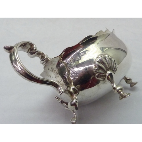 424 - A silver sauce boat standing on scallop mounted hoof feet; a silver toast rack, both early 20th cent... 