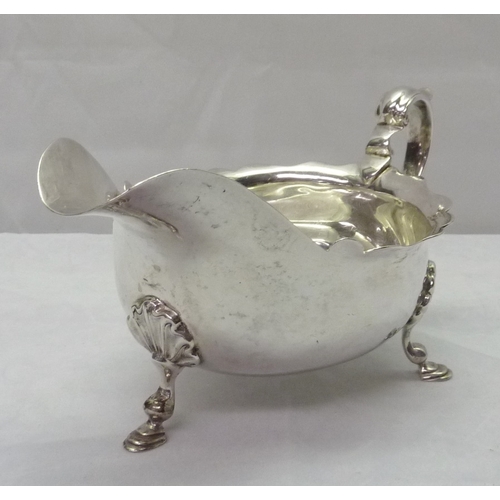 424 - A silver sauce boat standing on scallop mounted hoof feet; a silver toast rack, both early 20th cent... 