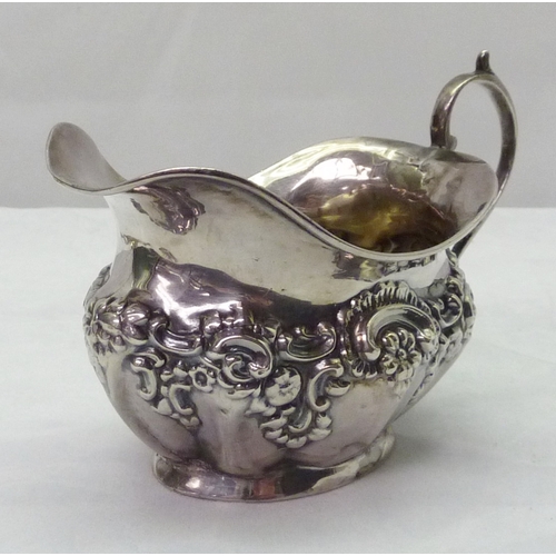 428 - A silver cream jug having repousse decoration, early 20th cent; a modern silver snuff box having dog... 