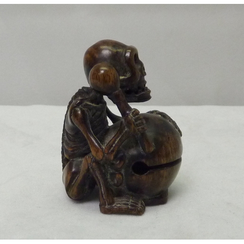 391 - A netsuke depicting a skeleton drummer, carved hardwood, signed to base