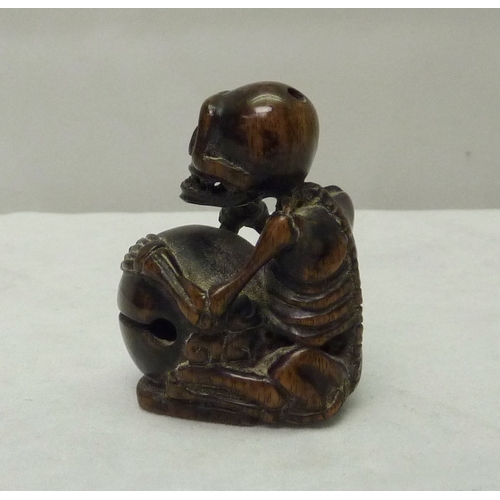 391 - A netsuke depicting a skeleton drummer, carved hardwood, signed to base